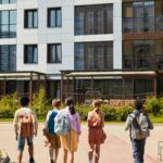 A group of teenagers walking towards a modern school building on a sunny day.